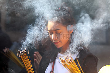 Macau  China  junge Frau betet im A-Ma Tempel mit angezuendeten Raeucherstaebchen