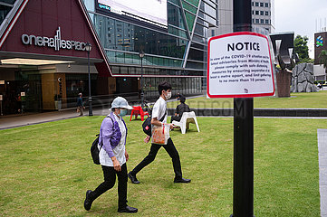 Singapur  Republik Singapur  Menschen mit Mundschutz gehen an Hinweis zu Safe Distancing Massnahmen vorbei