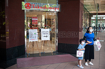 Singapur  Republik Singapur  Mutter und Kind mit Mundschutz vor einem Einkauszentrum