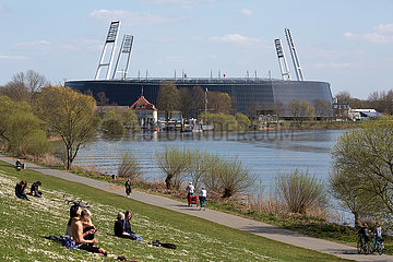 Deutschland  Bremen - Menschen geniessen die Sonne am Osterdeich an der Weser  hinten das Weserstadion vom SV Werder Bremen
