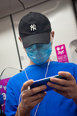 Singapur  Republik Singapur  Mann mit Mundschutz und Baseballkappe in einer U-Bahn