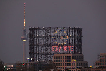 Berlin  Deutschland  Blick auf den Gasometer Schoeneberg mit dem Schriftzug stay home und den Berliner Fernsehturm bei Daemmerung