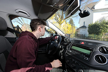 Berlin  Deutschland  junger Mann schaut vor der Fahrt mit dem Auto auf sein Navigationsgeraet