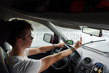 Berlin  Deutschland  junger Mann zeigt beim Autofahren den Mittelfinger