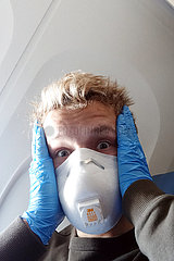 Minneapolis  USA  Teenager sitzt in Zeiten der Coronapandemie aengstlich mit Atemschutzmaske und Schutzhandschuhen in einem Flugzeug