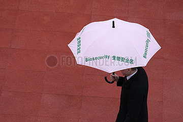 Conghua  China  Mann traegt einen Regenschirm mit dem Schriftzug Biosecurity