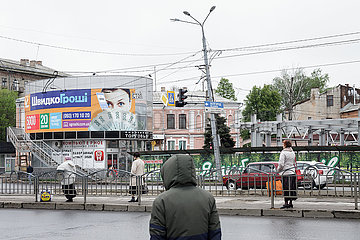 Passanten warten an einer Bushaltestelle in Charkiw