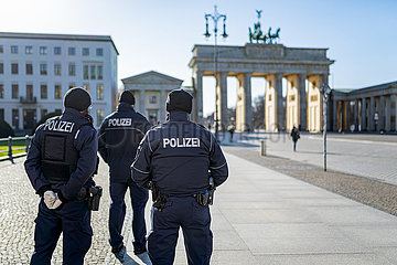 Berlin waehrend der Ausgangsbeschraenkung: Polizisten stehen auf dem sonst menschenleeren Pariser Platz am Brandenburger Tor