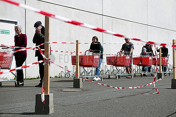 Deutschland  Bremen - Warteschlange wegen Corona: Kunden mit Einkaufswagen vor einem Baumarkt