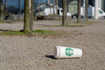 Leerer Becher der Firma Starbucks liegt auf dem Boden