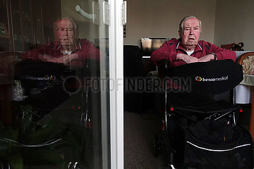 Berlin  Deutschland  Senior sitzt mit seinem Rollator an der geoeffneten Balkontuer seiner Wohnung
