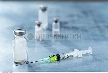 The syringe is placed beside the medicine bottle on slate