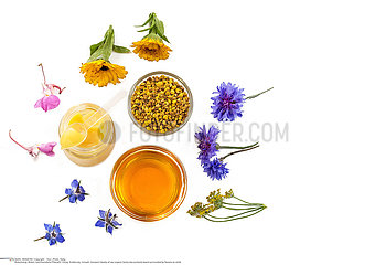 Variety of raw organic honey bee products board surrounded by flowers on white background