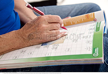 ELDERLY PERSON DOING CR-WORD PUZZLE