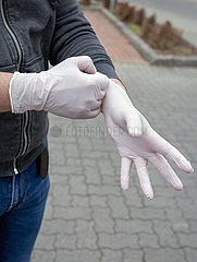 Berlin  Deutschland - Mann zieht sich Einmal-Handschuhe an