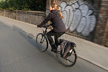 Berlin  Deutschland  Fahrradfahrerin faehrt ohne Helm auf einer Strasse