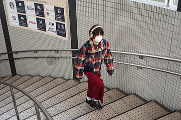 Kyoto  Japan  Frau mit Mundschutz geht die Treppe einer U-Bahnstation hoch