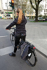 Berlin  Deutschland  Fahrradfahrerin steht ohne Helm an einer roten Ampel