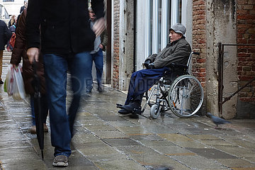 Venedig  Italien  alter Mann sitzt im Rollstuhl von Passanten ignoriert auf einer Strasse
