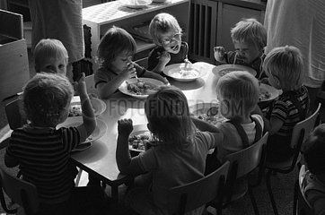 Berlin  Deutsche Demokratische Republik  Kleinkinder sitzen in einer Kinderkrippe zum Mittagessen an einem Tisch