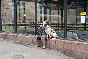 Helsinki  Finnland  Frau sitzt mit ihrem Hund vor dem Bahnhof der Hauptstadt