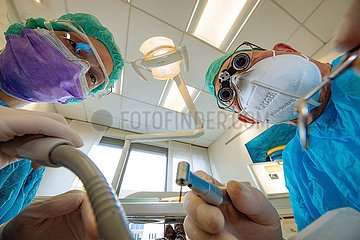 Zahnarzt und Zahnarzthelferin in besonderer Schutzkleidung
