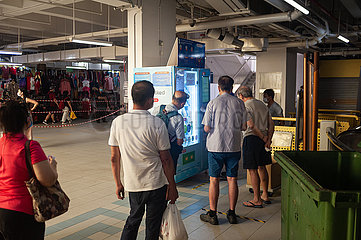 Singapur  Republik Singapur  Menschen mit Mundschutz vor einem Warenautomat mit wiederverwendbaren Schutzmasken