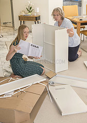 zwei Frauen bauen gemeinsam Ikea-Schrank auf