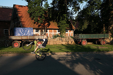 Deutschland  Heidenau - Junge auf dem Fahrrad auf Dorfstrasse
