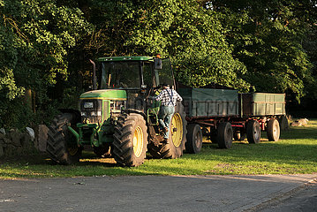 Deutschland  Heidenau - Landwirt steigt von seinem Traktor an einer Dorfstrasse
