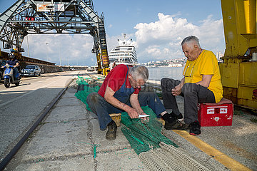Kroatien  Rijeka - Fischer am Pier bessert Netze aus