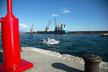 Kroatien  Rijeka - Kleines Motorboot verlaesst den Hafen  hinten ein Frachter
