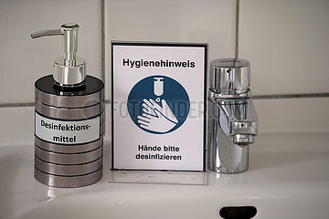Hoppegarten  Deutschland  Desinfektionsmittel in einem silbernen Seifenspender und Hinweisschild auf einem Waschbecken