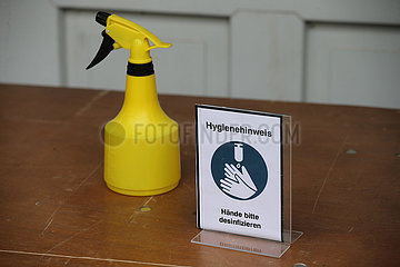 Hoppegarten  Deutschland  Desinfektionsmittel in einer gelben Spruehflasche und Hinweisschild auf einem Tisch