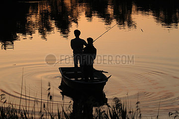 Dranse  Deutschland  Silhouette: Jugendliche in einem Boot angeln bei Sonnenuntergang in einem See