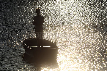 Dranse  Deutschland  Silhouette: Jugendlicher in einem Boot angelt am Abend in einem See
