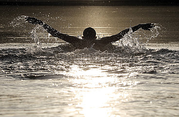 Walkmuehle  Deutschland  Jugendlicher schwimmt bei Sonnenuntergang im Baalsee