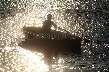 Dranse  Deutschland  Silhouette: Jugendlicher sitzt am Abend auf einem See in einem Ruderboot