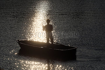 Dranse  Deutschland  Silhouette: Jugendlicher in einem Boot angelt am Abend in einem See