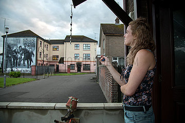 Grossbritannien  Derry - Junge Anwohnerin im katholischem Stadtteil Bogside  hinten ein katholisches Wandbild  das an den irischen Freiheitskampf gegen die Briten erinnert