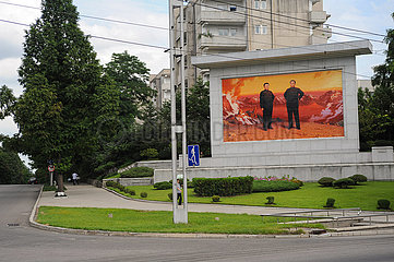 Pjoengjang  Nordkorea  Gedenktafel mit den Portraits von Kim Il-sung und Kim Jong-il am Strassenrand