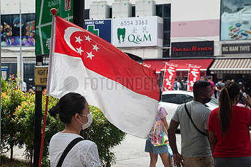 Singapur  Republik Singapur  Frau mit Mundschutz vor einer Nationalflagge