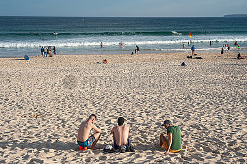 Sydney  Australien  Menschen sitzen am beruehmten Strand von Bondi Beach im Sand