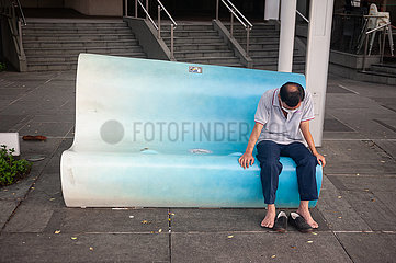 Singapur  Republik Singapur  Mann mit Mundschutzmaske sitzt allein auf Bank in Clarke Quay
