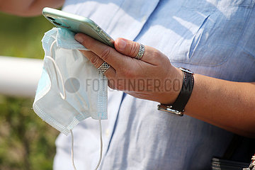 Hoppegarten  Deutschland  Smartphone und Mund-Nasen-Schutz in der Hand einer Frau