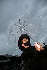 Hannover  Deutschland  Mann mit Hut und Regenschirm traegt einen Mund-Nasen-Schutz