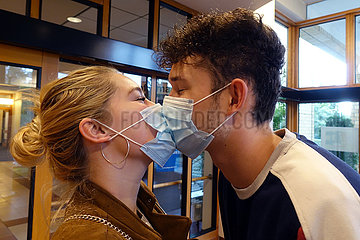 Berlin  Deutschland  junges Paar mit Mund-Nasen-Schutz kuesst sich