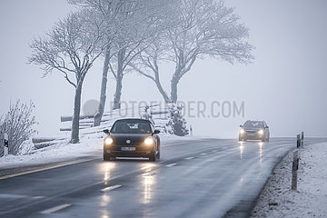 Autos fahren auf einer Landstrasse durch eine Winterlandschaft  Winterberg  Sauerland  Nordrhein-Westfalen  Deutschland