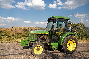 Republik Moldau  Horodiste - Weinbauern mit dem Traktor unterwegs auf der Landstrasse. Er lenkt mit den Fuessen.