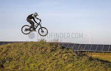 Mountainbikefahrer auf Mountainbike Arena vor Solarpark und Windrad  Dortmund  Ruhrgebiet  Nordrhein-Westfalen  Deutschland
